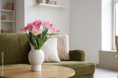 Vase with tulips on table in light living room