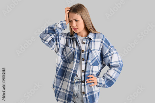 Worried young woman on grey...