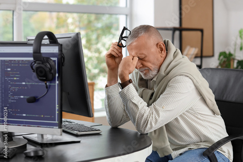 Tired mature programmer sit...