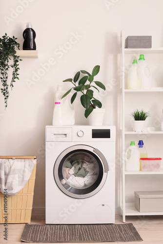Interior of laundry room with washing machine, basket and shelf unit