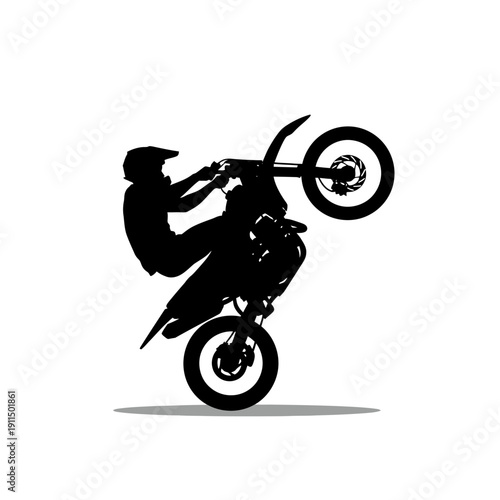 Silhouette of a motocross rider performing a wheelie stunt