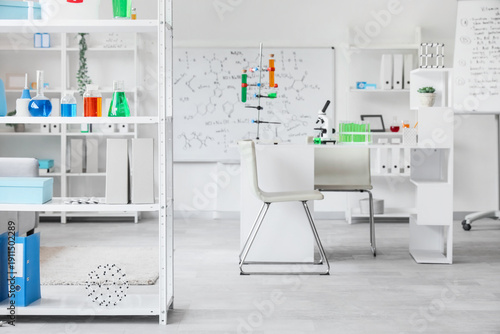 Interior of laboratory with workplace, shelf units and chemical glassware