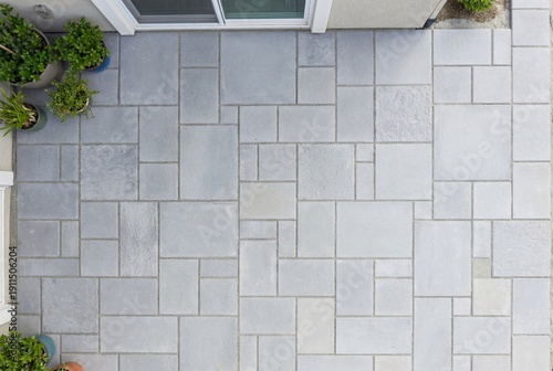 Top down view of a light grey concrete paved patio with a patterned stone layout