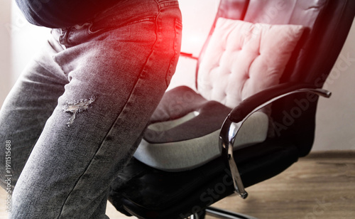 Person using orthopedic seat cushion for lower back pain, finding support for spinal discomfort. Ergonomic chair accessory aids posture and provides relief from disc issues. Medical aid for chronic