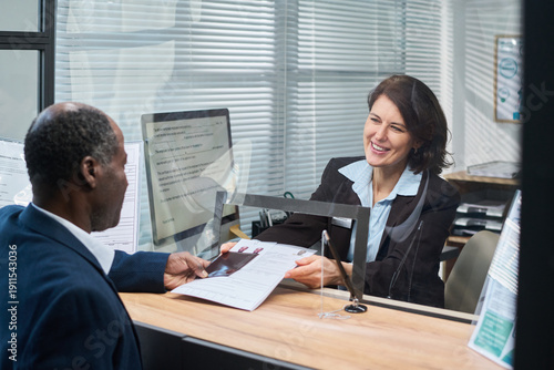 Foto Middle aged Caucasian woman smiling while assisting middle aged Black man submit