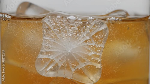 A close-up shot captures ice in a drink with fractured center; effervescence visible