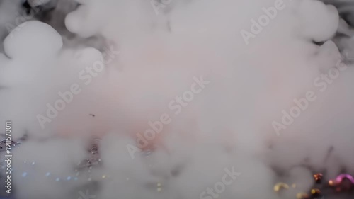 An abstract image featuring smoke, tiny metallic spheres, and small particles