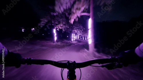 Riding a bicycle at night with purple lights.