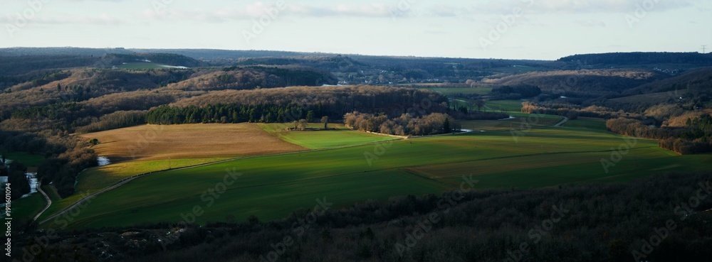 Obraz premium Golden Hour Glow Over Expansive Rural Fields and Forested Hills, French Countryside