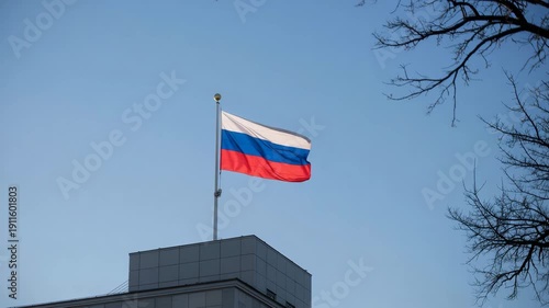 Russian flag waving on modern building rooftop against clear blue sky