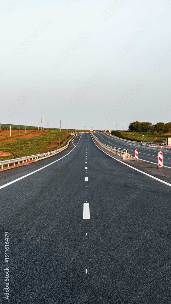 Fototapeta premium Highway stretching far with no visible cars on a clear day in an open landscape