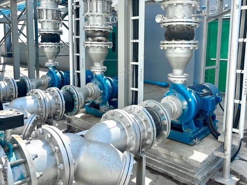 Industrial water pump station and pipeline system installed outdoors. Featuring high-pressure centrifugal pumps, silver metallic pipes, and professional cable management, this infrastructure setup is 