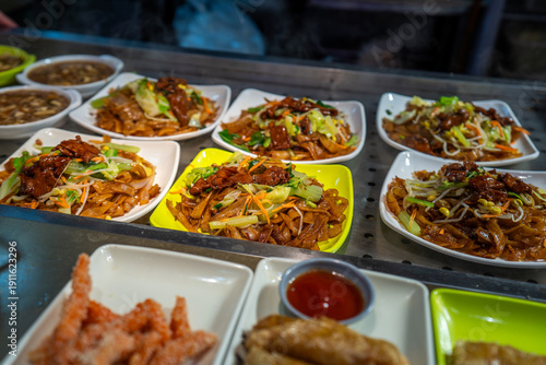 Photography Local food and snacks including pork, Scallion Oil Noodles, intestines and seafood brochettes displayed in a popular market at night, Shanghai, China