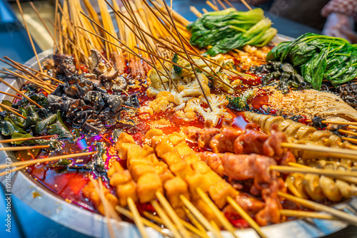 Local food and snacks including pork, Scallion Oil Noodles, intestines and seafood brochettes displayed in a popular market at night, Shanghai, China.