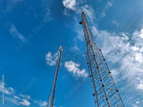 Fényképezés Two tall metal cell towers on blue background