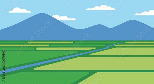 Broad panoramic view of lush green terraced rice paddy fields with a winding water channel leading towards a distant blue mountain range under a clear sky, depicting agricultural landscape.
