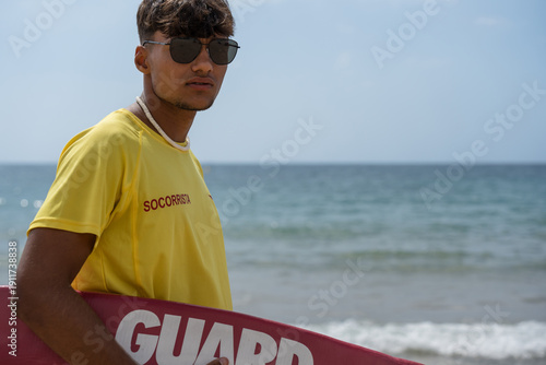 Fotografie Lifeguard holding rescue board watching over swimmers