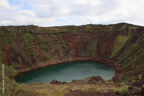 Kerið crater lake within the Grímsnes volcanic field in Iceland, part of the Tjarnarhólar crater row along the Golden Circle near Þingvellir National Park under overcast sky.