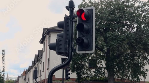 Classic British traffic light with a tilted position on a city street