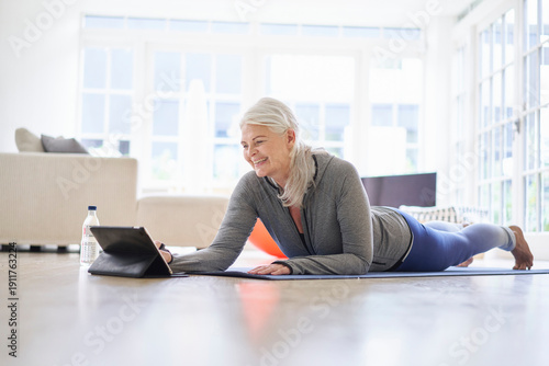 Smiling senior woman looking at digital tablet while e-learning exercises from digital tablet in apartment