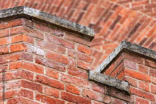 A detailed close-up of red brick walls featuring aged mortar, weathered stone caps, and layered parapet edges, capturing historic architectural textures and the rustic charm of brick construction