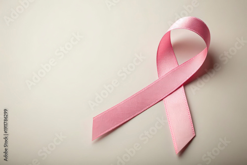 Pink awareness ribbon symbolizing breast cancer support and hope on a light surface
