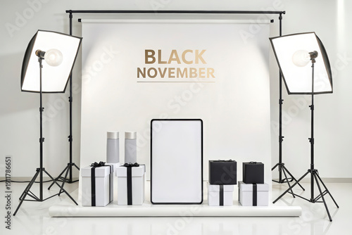 Studio with golden BLACK NOVEMBER text and blank tablet with various gift boxes for a festive sale