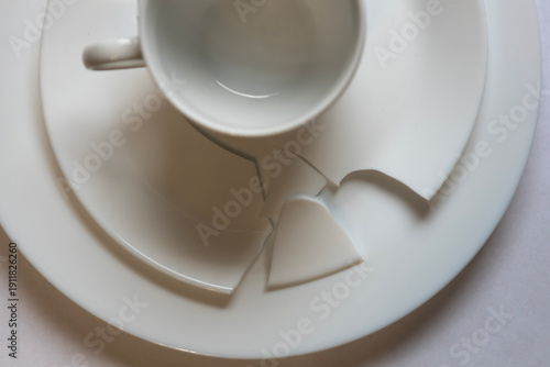Broken cup and plate set in a clean setting during daylight hours in a home kitchen environment