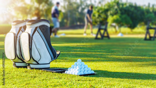 Schilderij op canvas Golf bags and golf balls at a practice area in the afternoon sun with players in