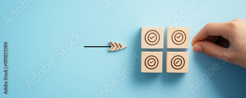 Goal achievement and business success concept with hand placing wooden block with target icon among check mark blocks on blue background for task management, strategy planning, and project milestone