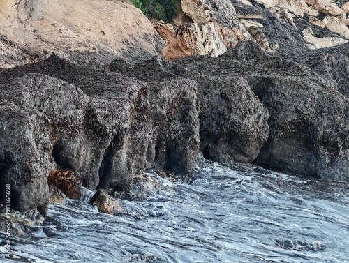 Waves over weathered rocks and pools, Sea surge causes erosion on coastal rock formations and pools
