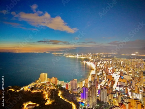 Foto Urban seaside scene during twilight hours, Vibrant nighttime cityscape along sho