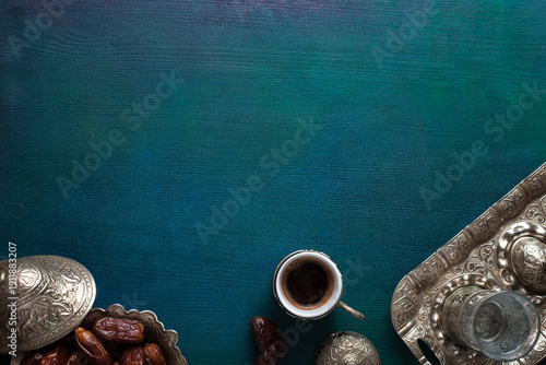 Cup of coffee, glass of water and bowl with date fruits on wooden table painted  blue-green. Top view. Ramadan background.
