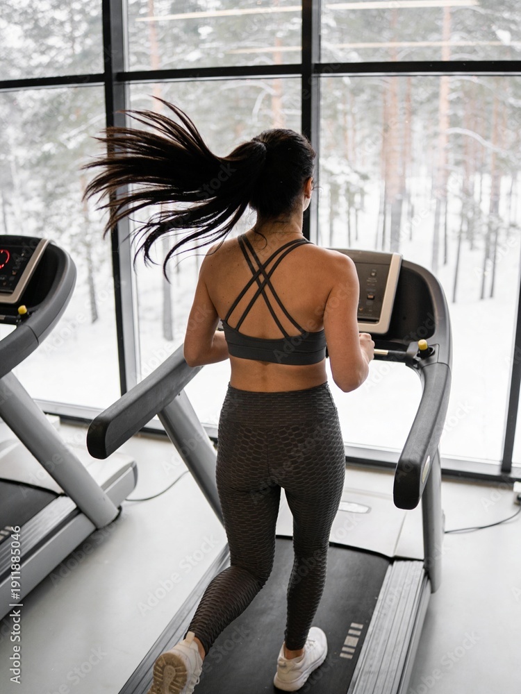 Fototapeta premium A woman running on a treadmill in a gym
