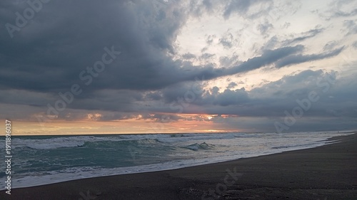 Sunset seascape panorama with dramatic cloud formations, rolling tide, reflective water surface, idyllic beach scene for meditation relaxation nature background.