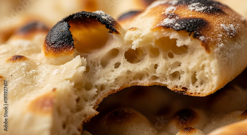 Close-up macro shot of a freshly baked, airy flatbread with crispy, charred edges, showcasing its delicate texture and porous structure, perfect for culinary use and food photography