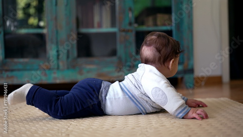 Baby on tummy lifting head, focused expression, exploring living room, early stages of learning to crawl, developing motor skills, home environment, attentive and curious