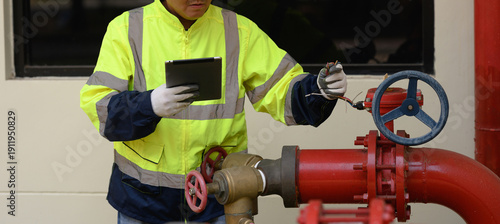 The focus is on a technician's hands inspecting the fire pump system of a large building.