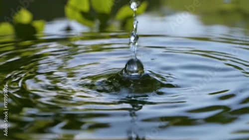 A close-up of a water droplet on a leaf reflecting a serene pond.