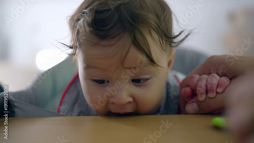 Baby hesitant to try solid food, close-up of reluctant expression, spoon near mouth, nurturing mother guiding, first-time eating, gentle introduction in home setting