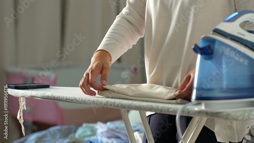 Hands neatly folding clothes after ironing, organized and precise, close-up view of domestic chores, calm and focused task, home organization and cleanliness