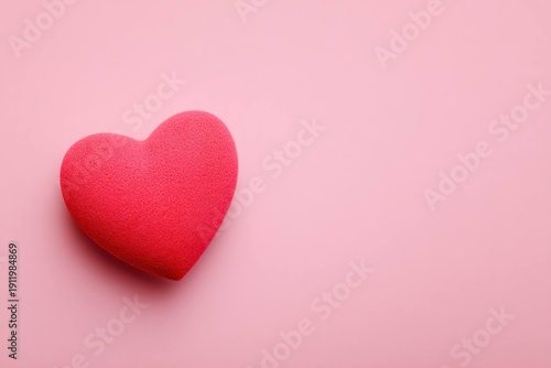 Red heart shape on pink background, symbolizing love, romance, and affection with copy space for text or design in Valentine or relationship concept image.