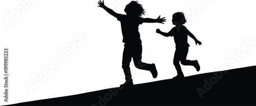 Two children running and playing on a hill in silhouette
