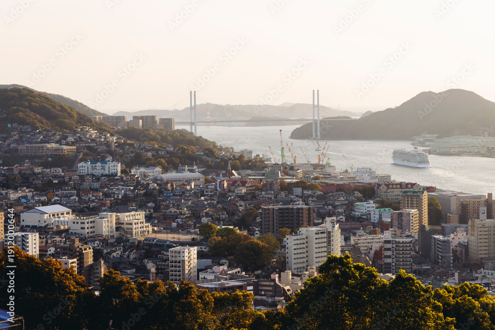 Fototapeta premium Nagasaki panorama, Japan, sunset aerial view, with city skyline, port and mountains, seen from Kazagashira mount park, in spring sunny day with a blue sky, Nagasaki prefecture, Kyushu island region