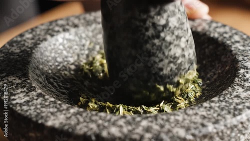 Pestle Grinding Herbs in Mortar Closeup.