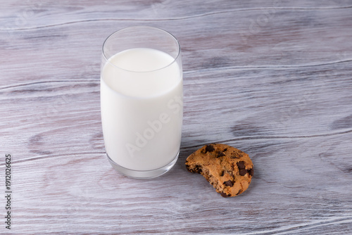 Chocolate chip cookie lies near a glass of milk. Calcium-rich milk.