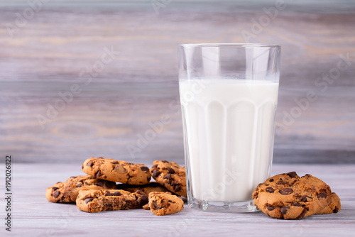A stack of chocolate chip cookies lies near a glass of milk. Calcium-rich milk.