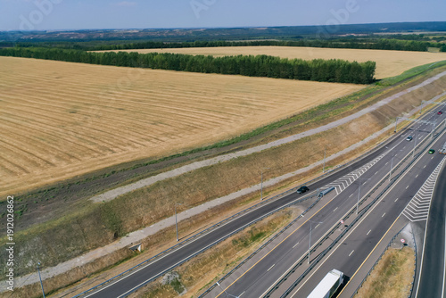 Aerial photography of agricultural fields in Russia. Beautiful views. Highway along the fields. Sunny day.