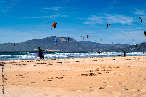 Kitesurfer walks on beach with surfboard, Tarifa, Spanish surfing spot.