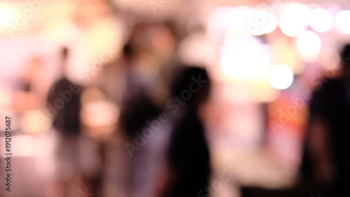 A blurry image of people in a crowded area. The people are wearing black and the scene is dimly lit